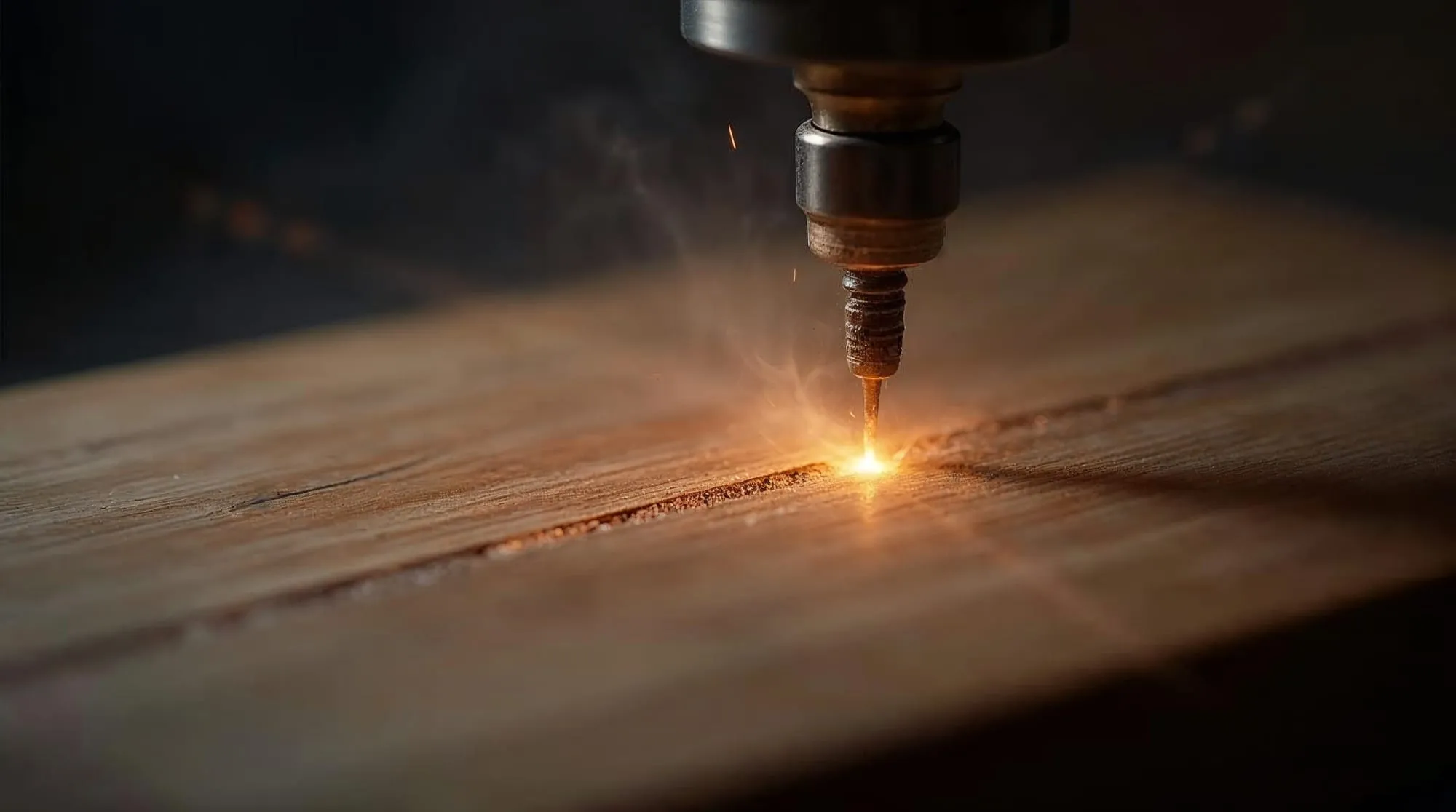 Gros plan d'un laser gravant une ligne dans du chêne